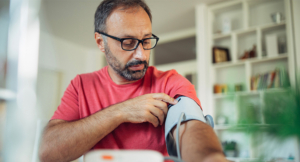 Mature mail applying a blood pressure cuff to his arm